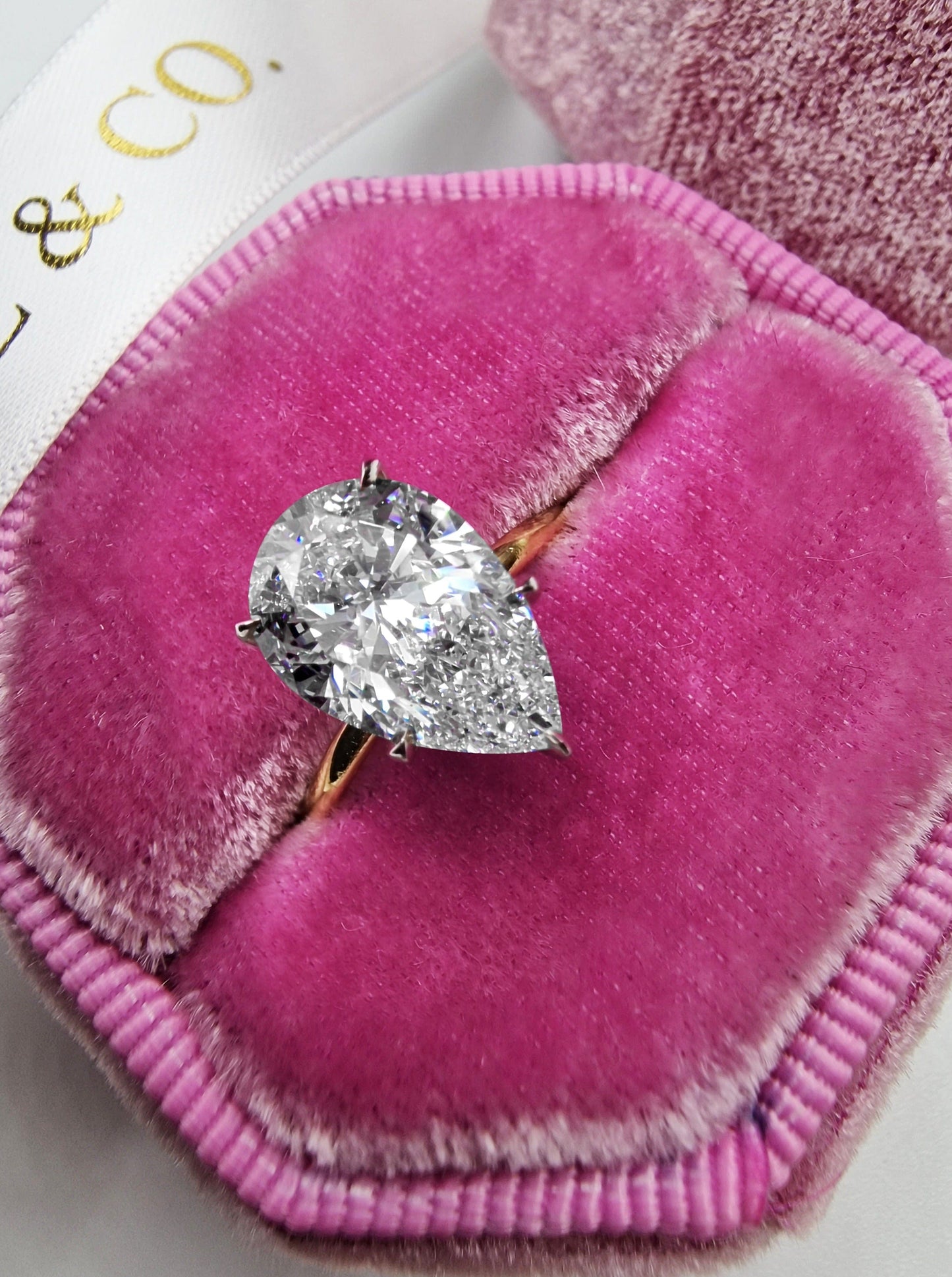 Pear-shaped diamond ring in a pink velvet jewelry box.