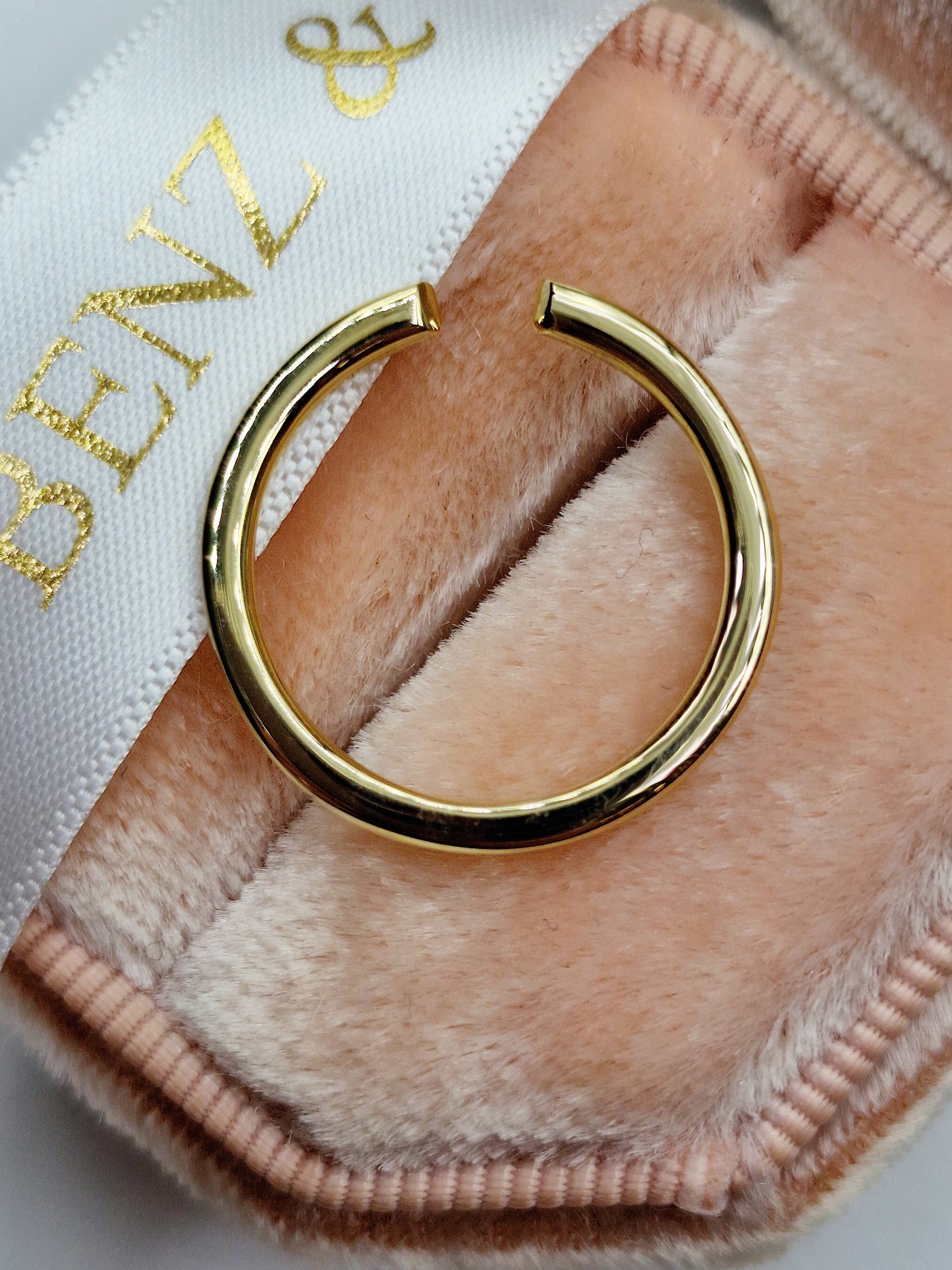 Gold open ring on pink velvet.