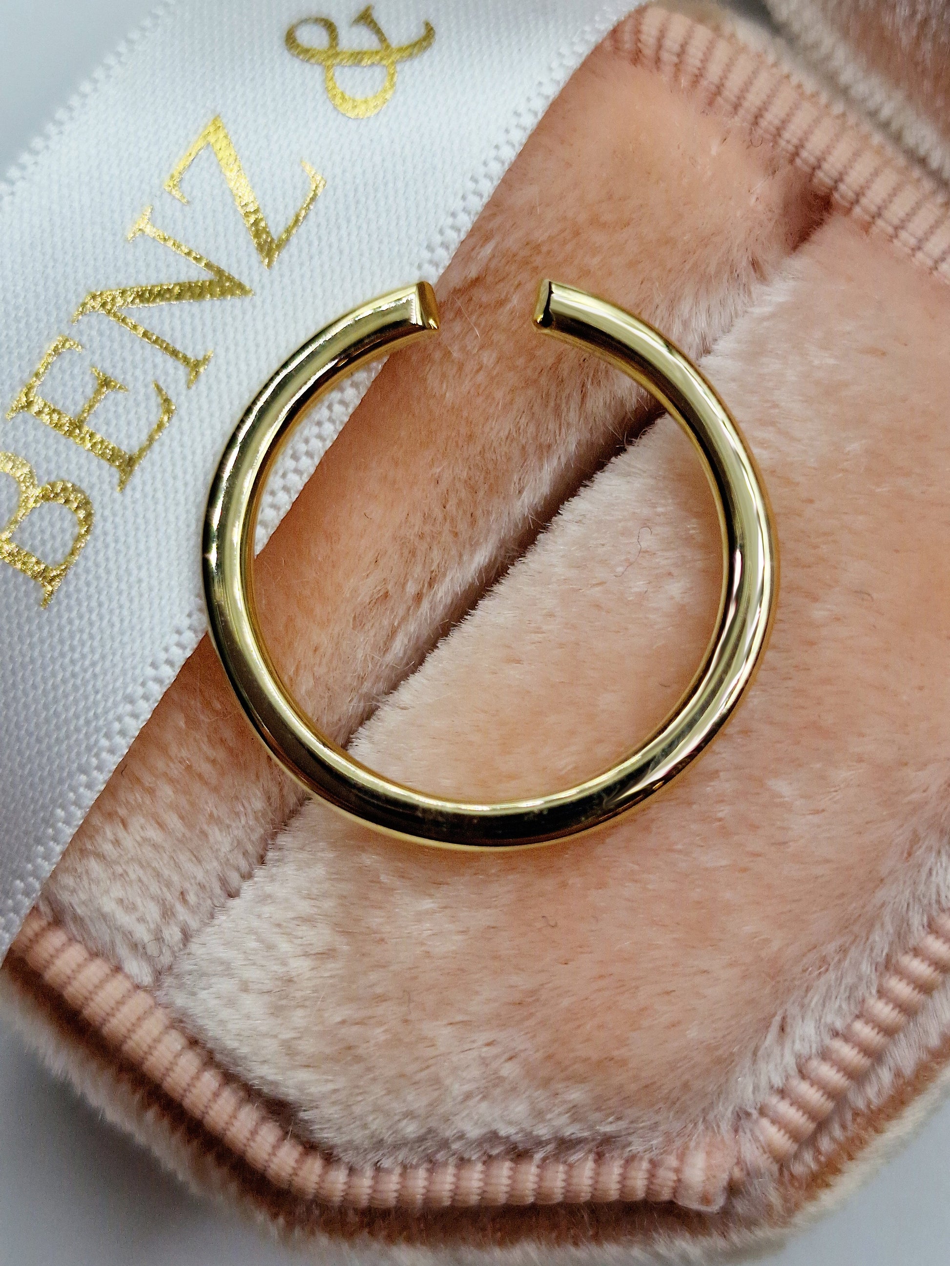 Gold open ring on pink velvet.