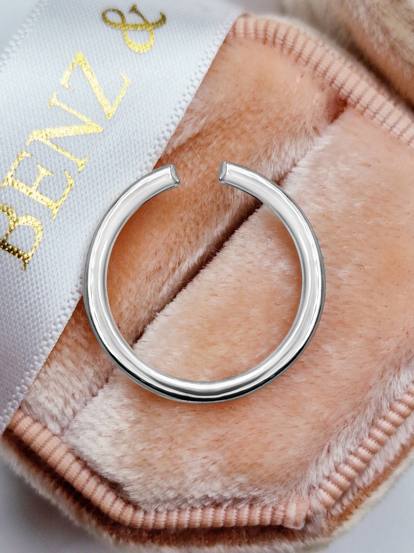 Silver ring on pink velvet.