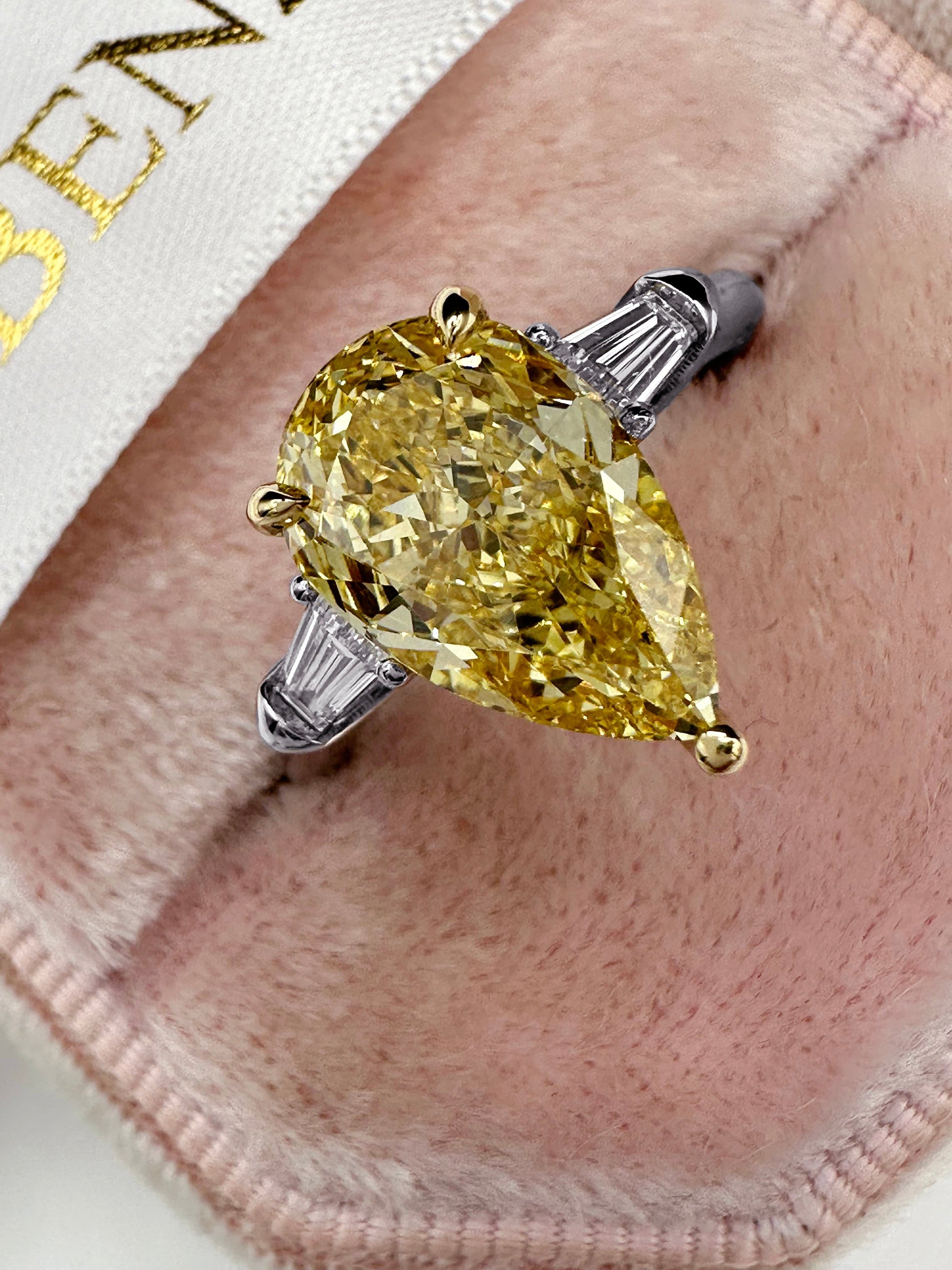 Yellow pear-shaped diamond ring on pink velvet.
