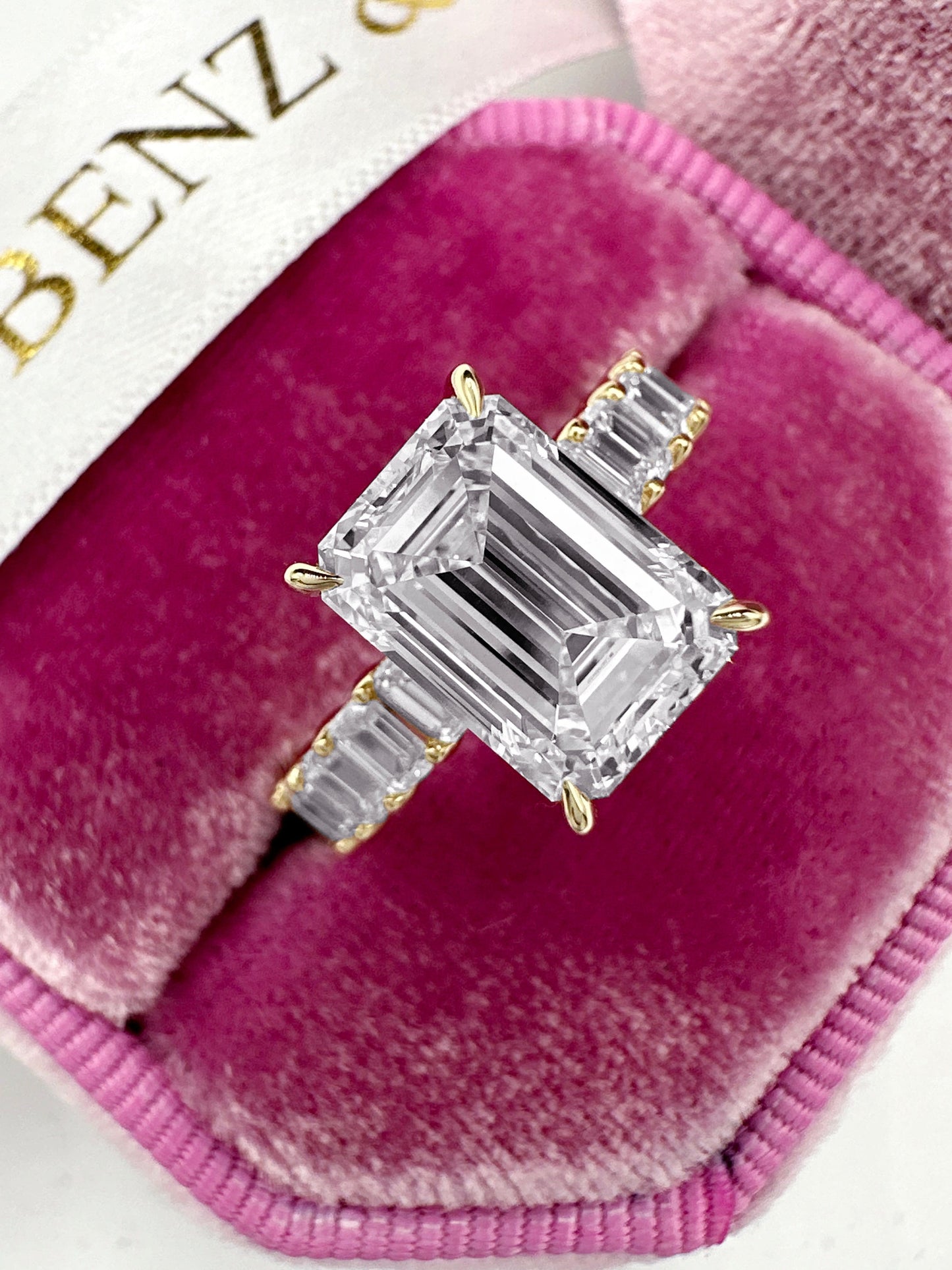 Emerald cut diamond engagement ring with side diamonds and hidden halo.