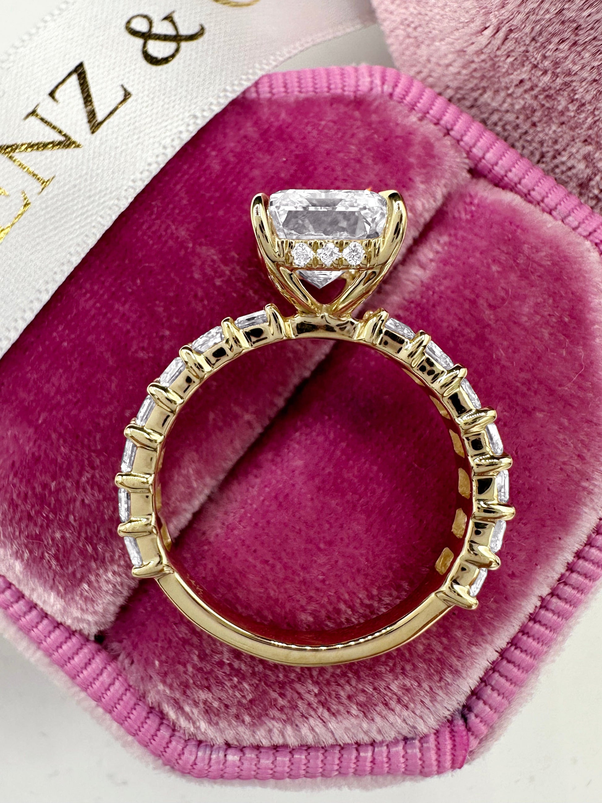 Emerald cut diamond ring with side diamonds and hidden halo.