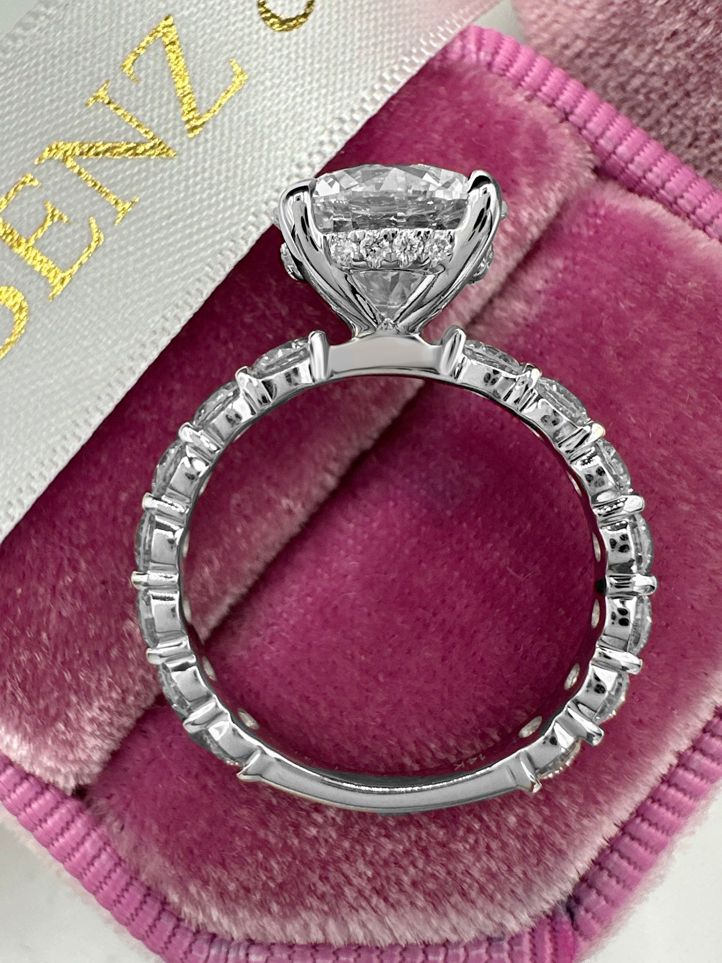 Round cut diamond engagement ring with side diamonds and hidden halo.