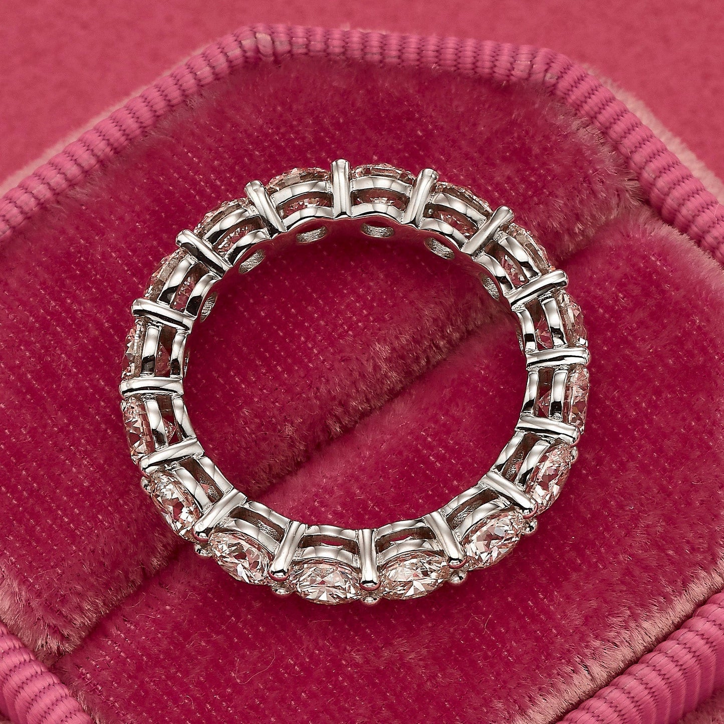 Diamond eternity ring on pink velvet.