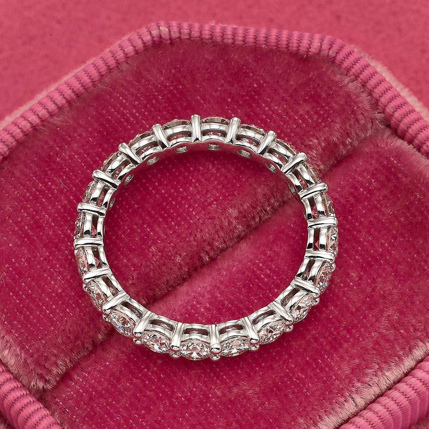 Diamond eternity ring on pink velvet.