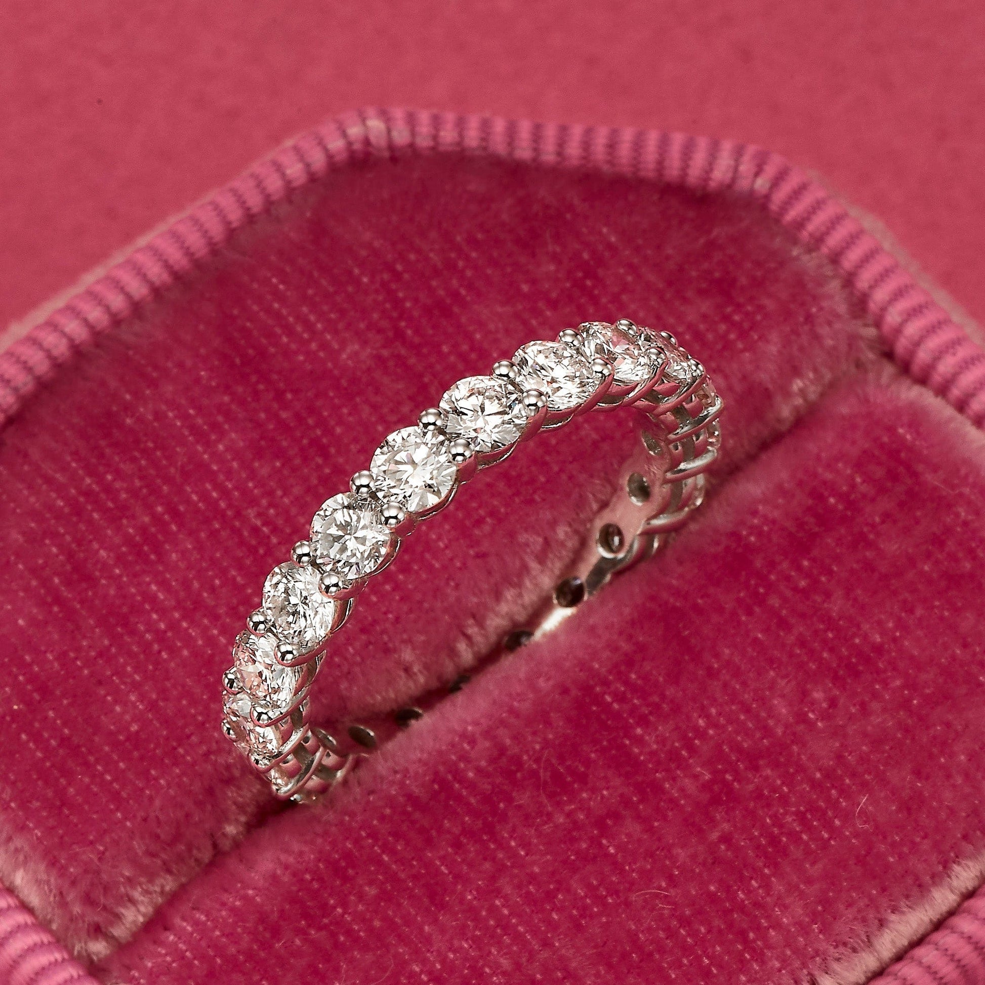 Diamond eternity ring on a pink velvet background.