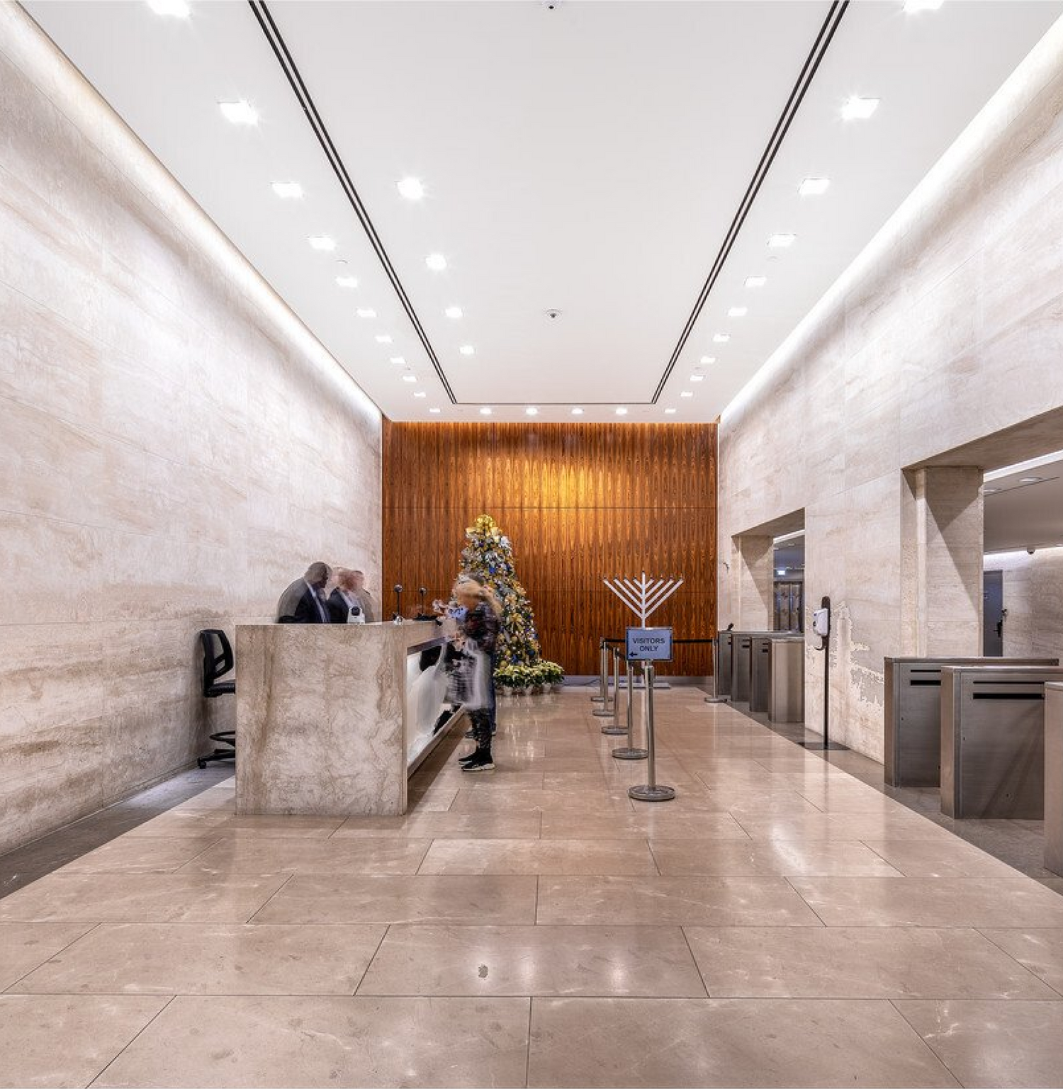 Modern office lobby with reception desk and security turnstiles.