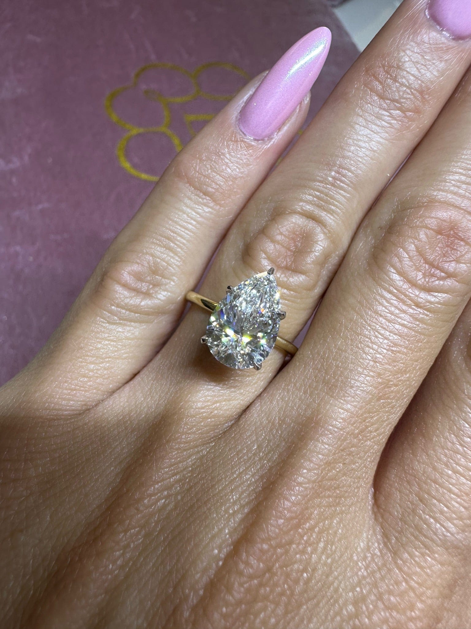 Hand with pear-shaped diamond ring.
