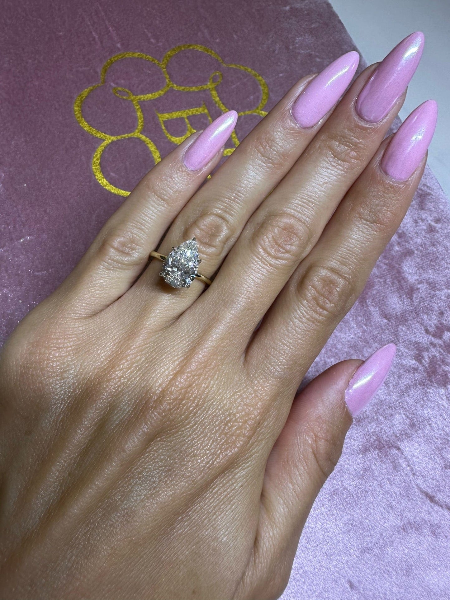 Hand with engagement ring and pink nails.