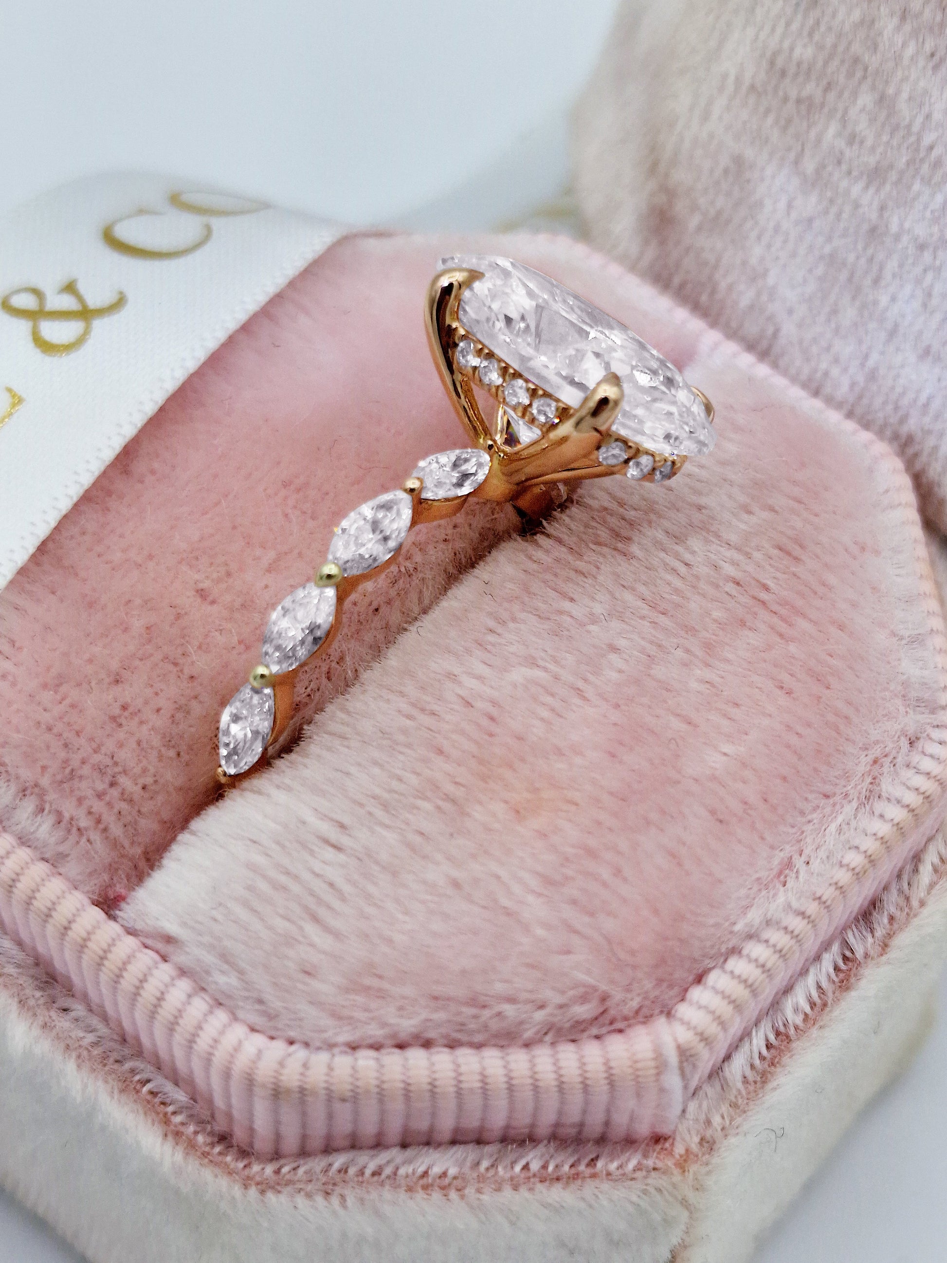 Oval diamond engagement ring with marquise side stones, rose gold.