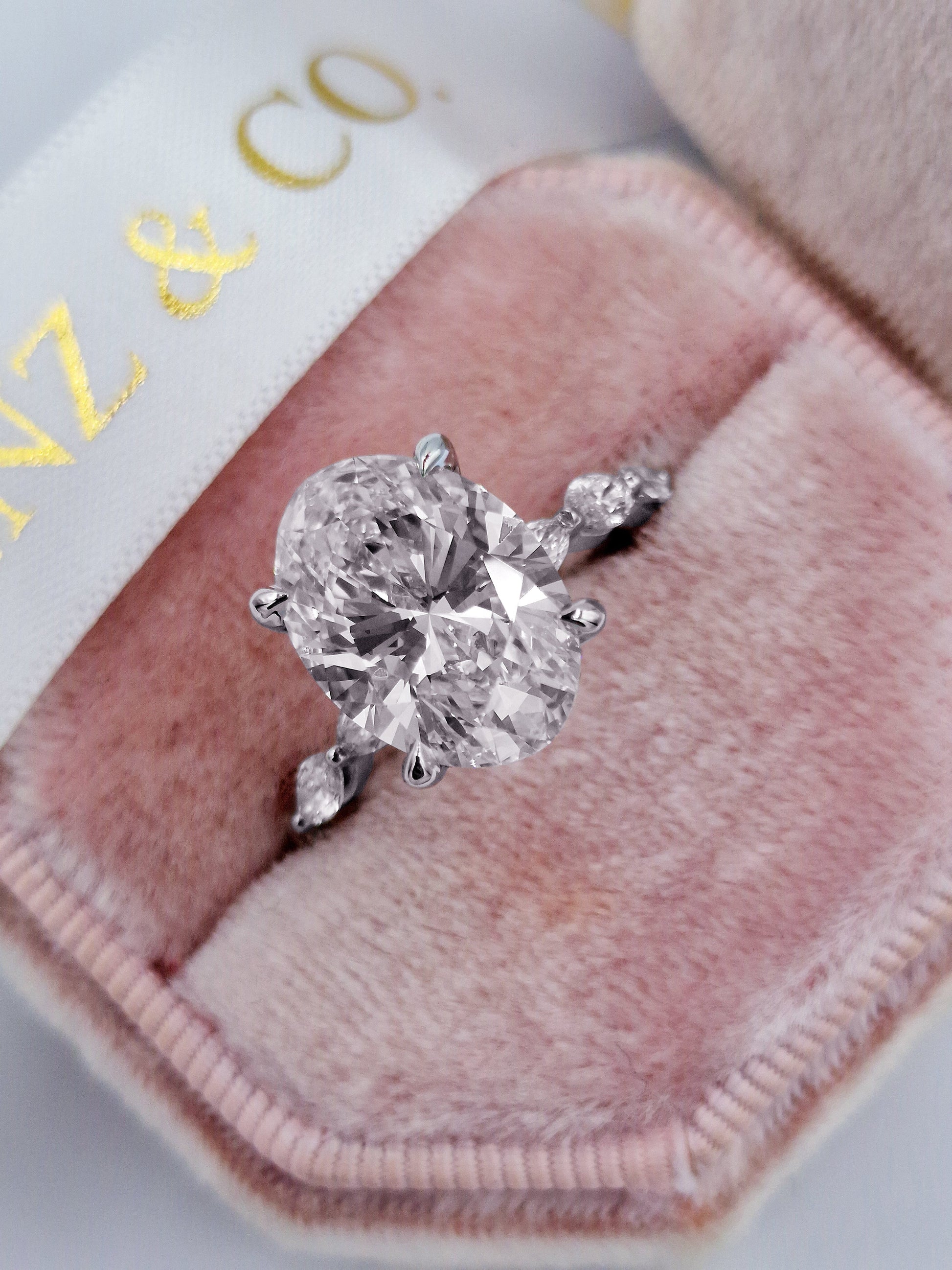 Oval diamond engagement ring with marquise accents and white gold band