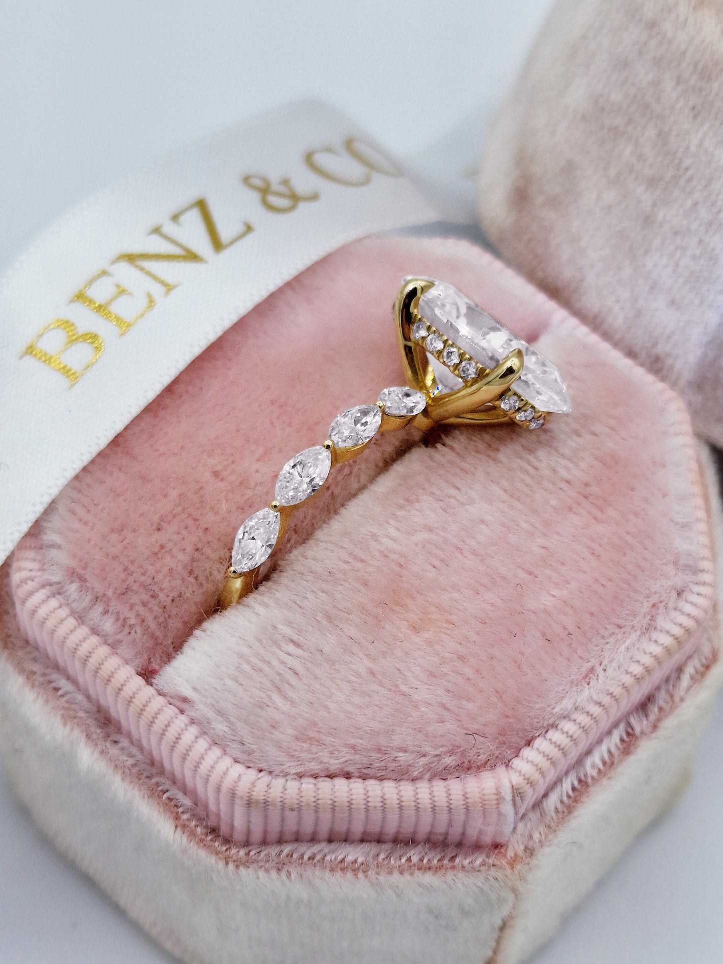 Oval diamond engagement ring with marquise side stones in yellow gold