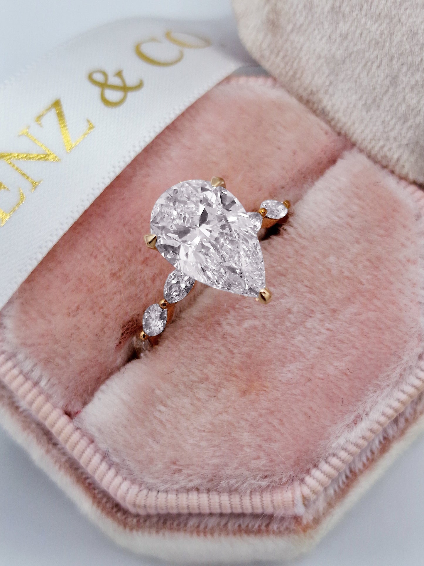 Pear diamond engagement ring with marquise side stones and rose gold band