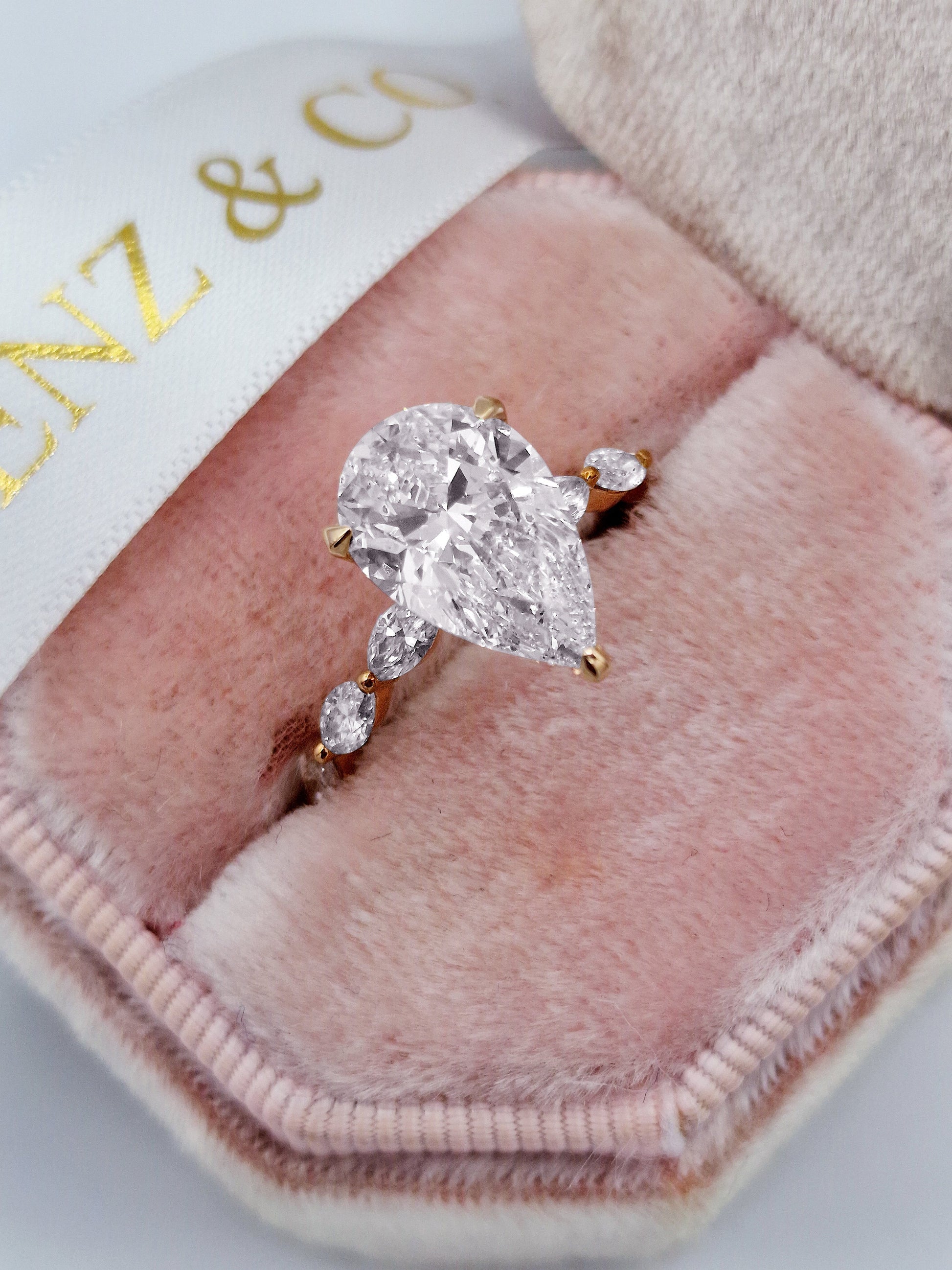 Pear diamond engagement ring with marquise side stones and rose gold band