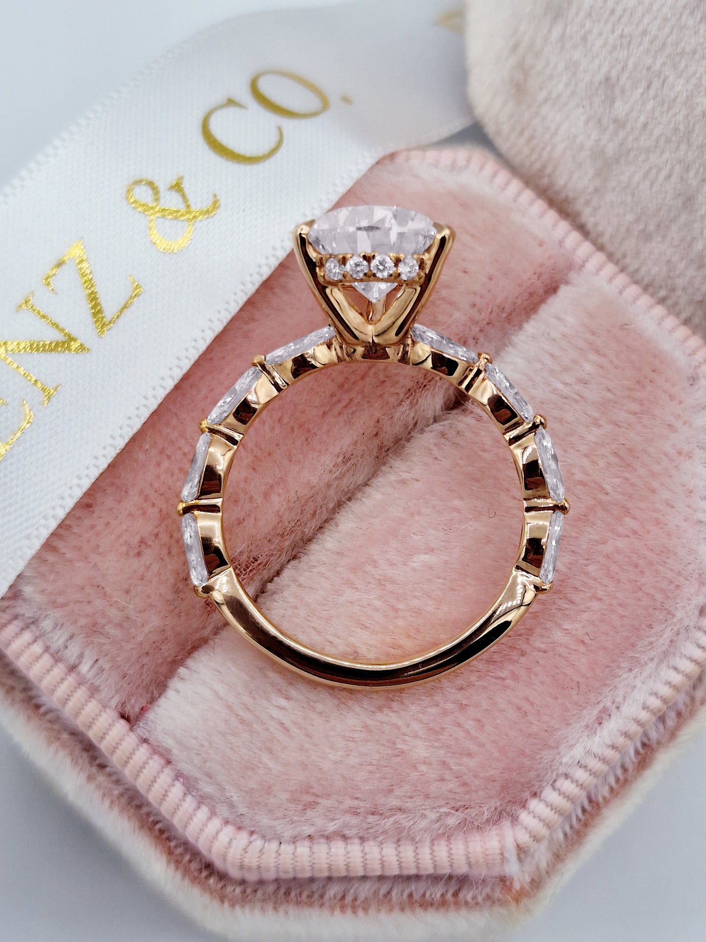 Rose gold pear diamond engagement ring with marquise side stones.