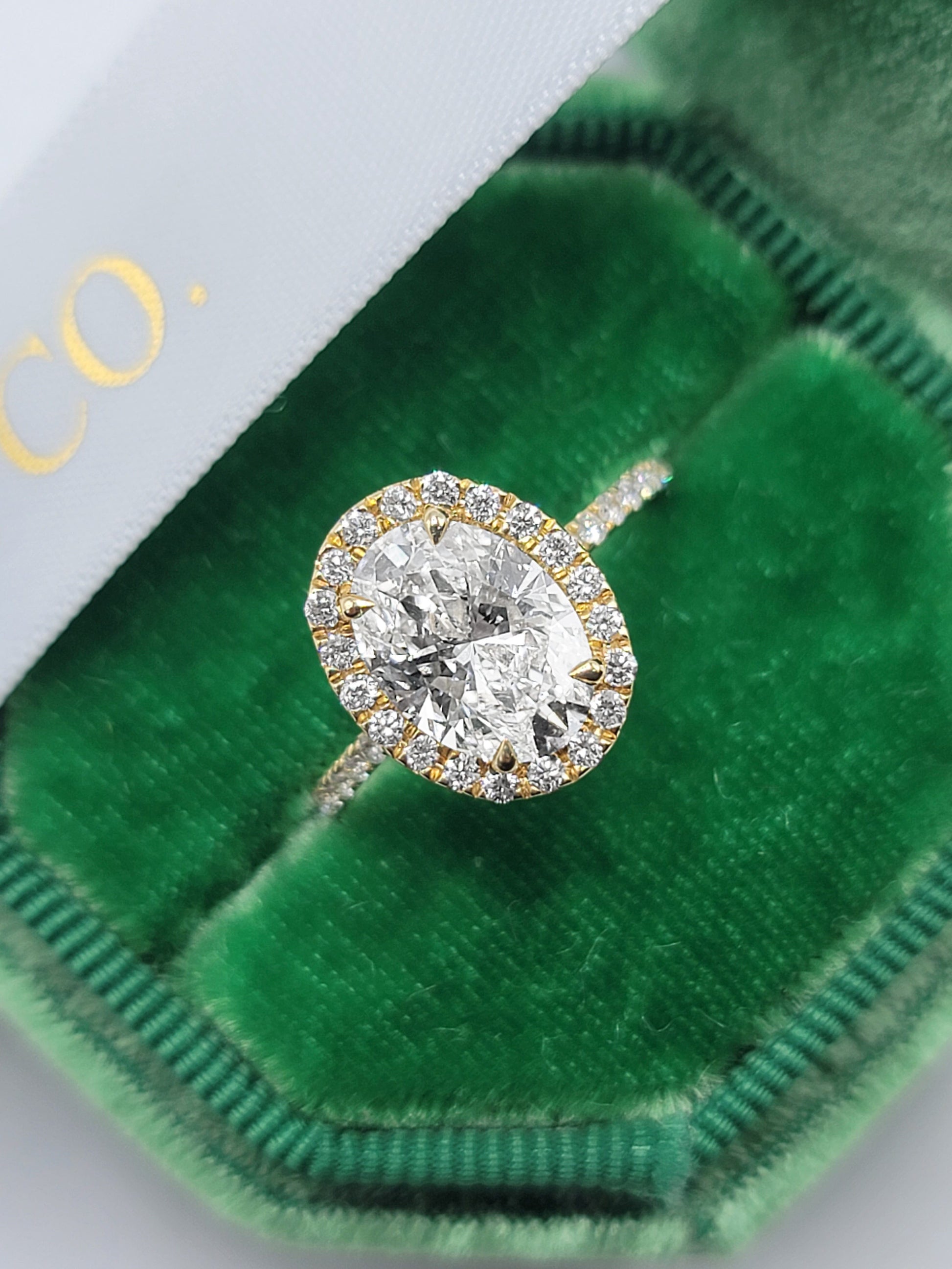 Oval diamond engagement ring in a green velvet box.