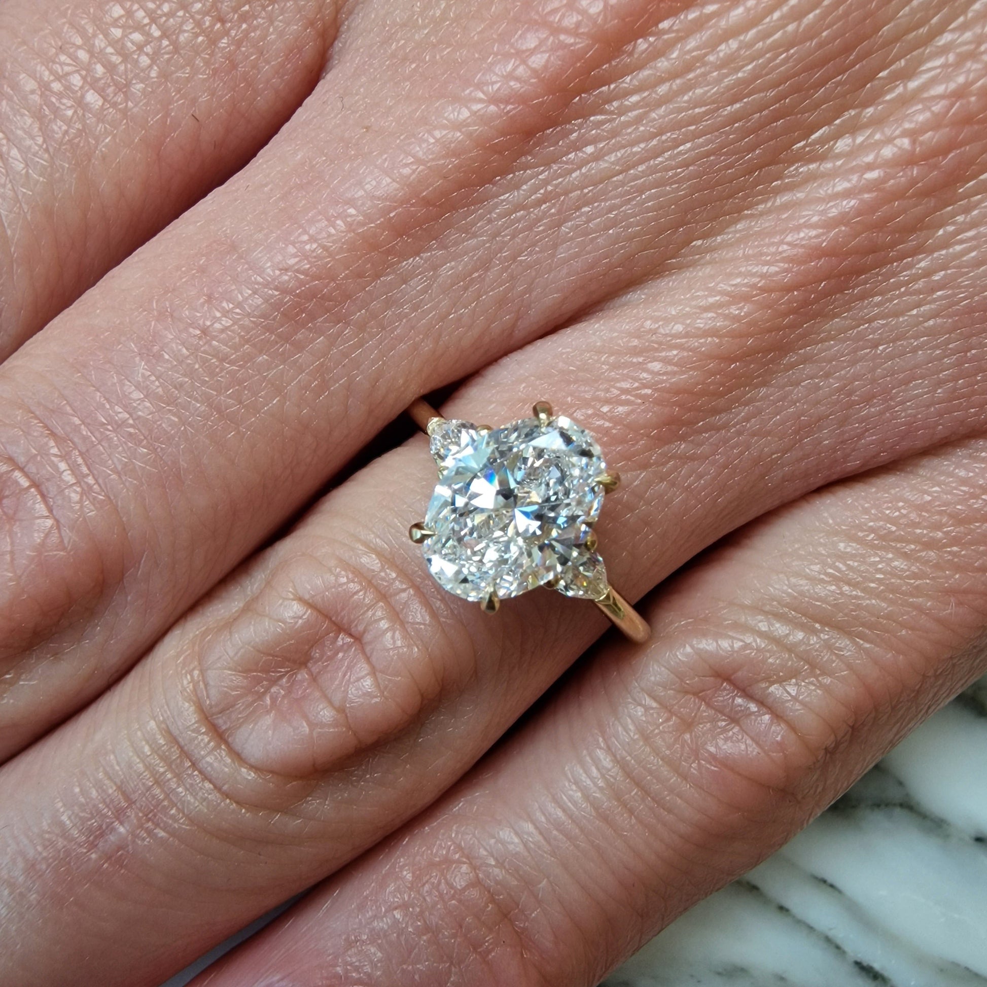 Hand wearing an oval diamond ring.