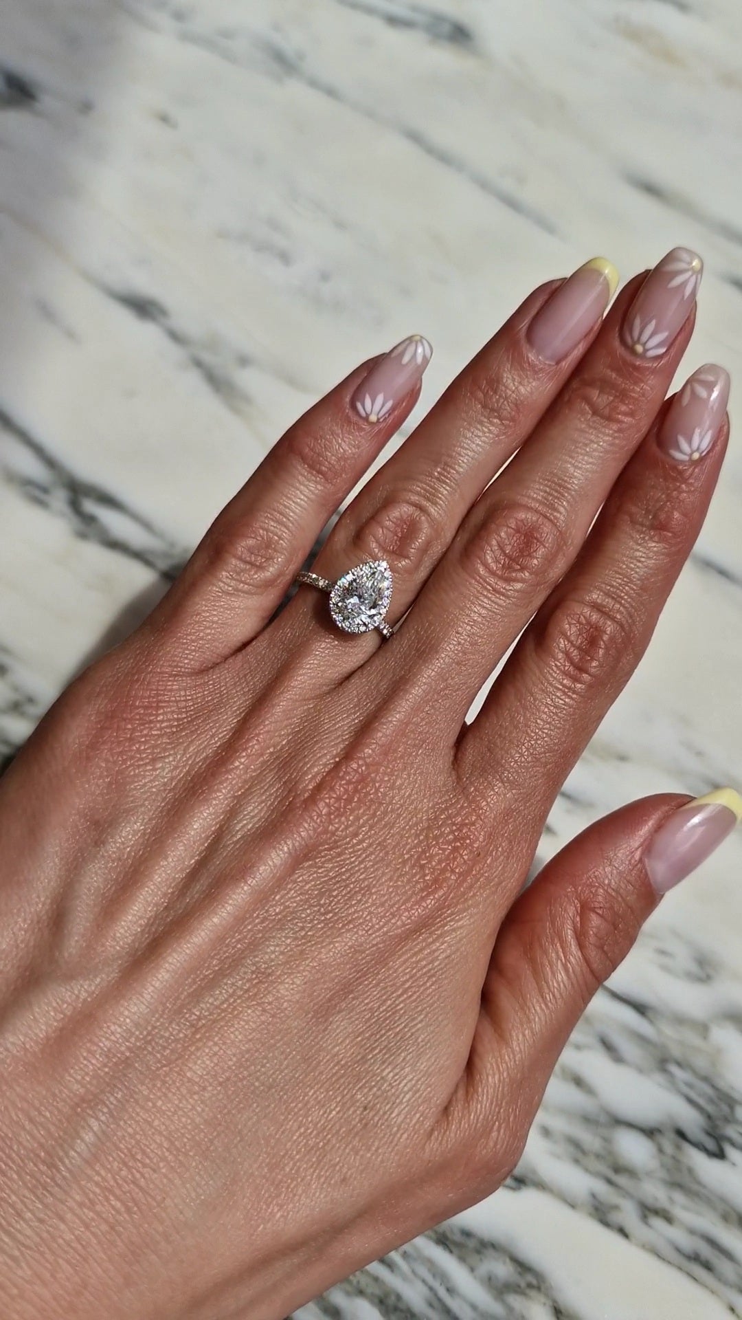 On-hand-image-of-pear-shaped-halo-diamond-ring-2-carat